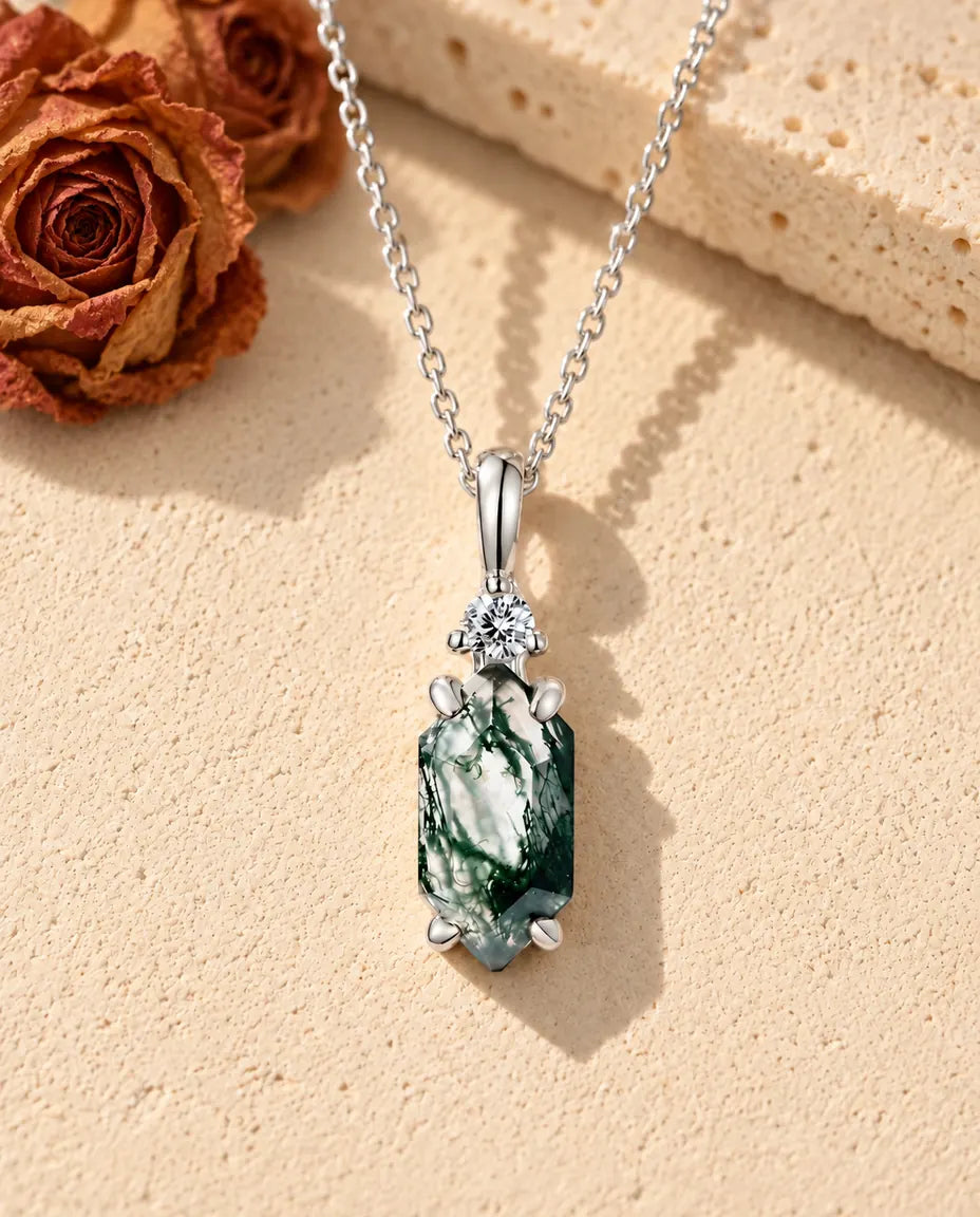 Moosachat Kette mit schmalem Sechseck aus 925 Sterlingsilber - auf heller Strukturfläche neben einem Travertinblock liegend