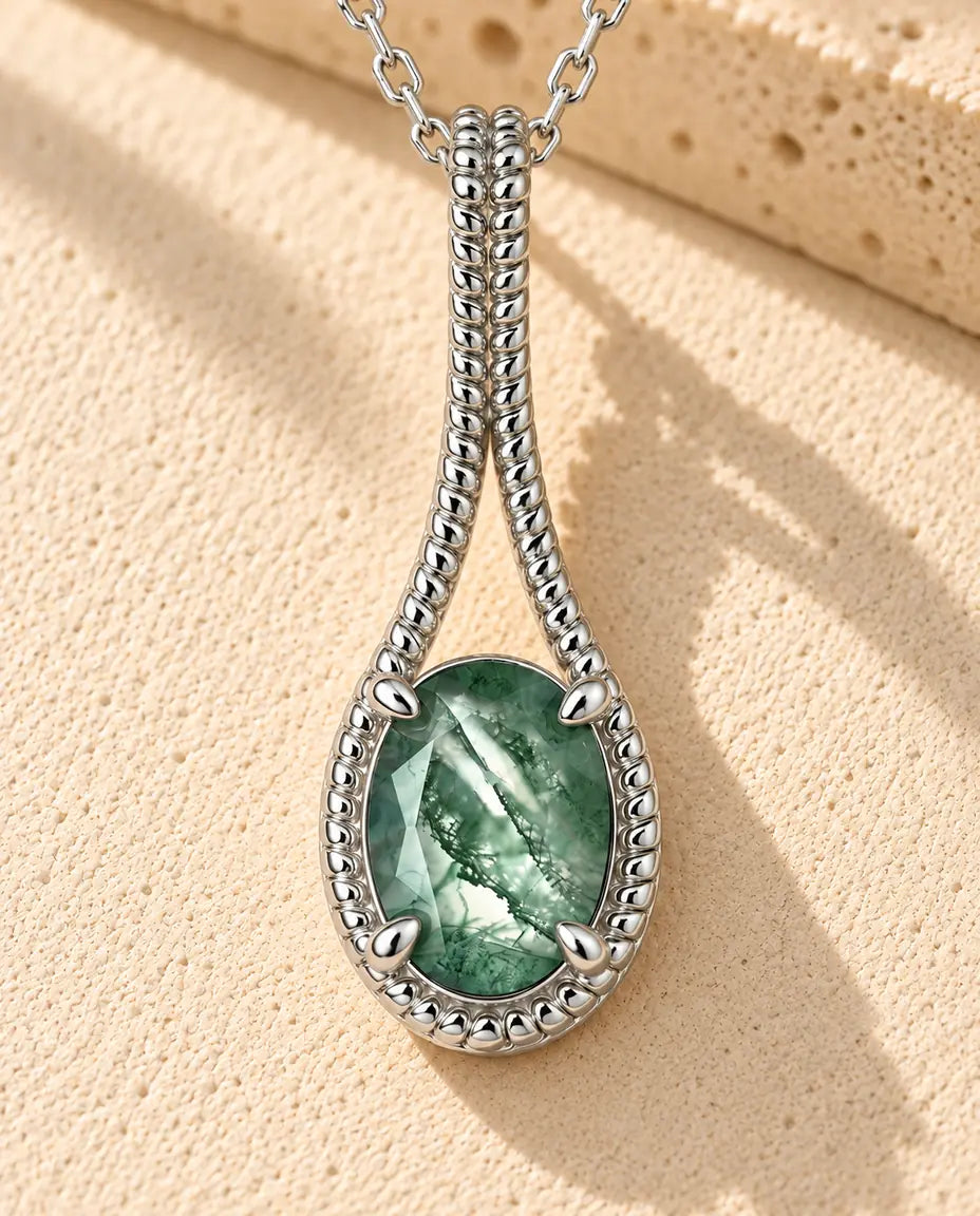 Ovale Moosachat Kette aus 925 Sterlingsilber - auf heller Strukturfläche neben einem Travertinblock liegend