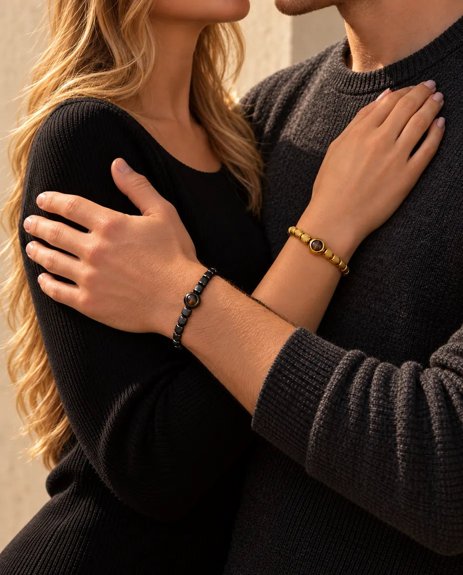 Paar in einer Umarmung, sie trägt das goldfarbene Perlenarmband mit Bild im Stein, er das schwarze