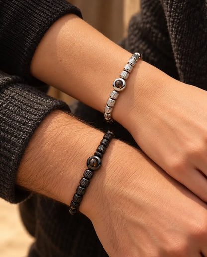 Nahaufnahme ihrer und seiner Handgelenke mit passenden Perlenarmbändern in silberfarben und schwarz