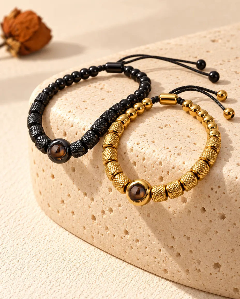 Schwarzes und goldfarbenes Partner-Perlenarmband über einem Travertinblock