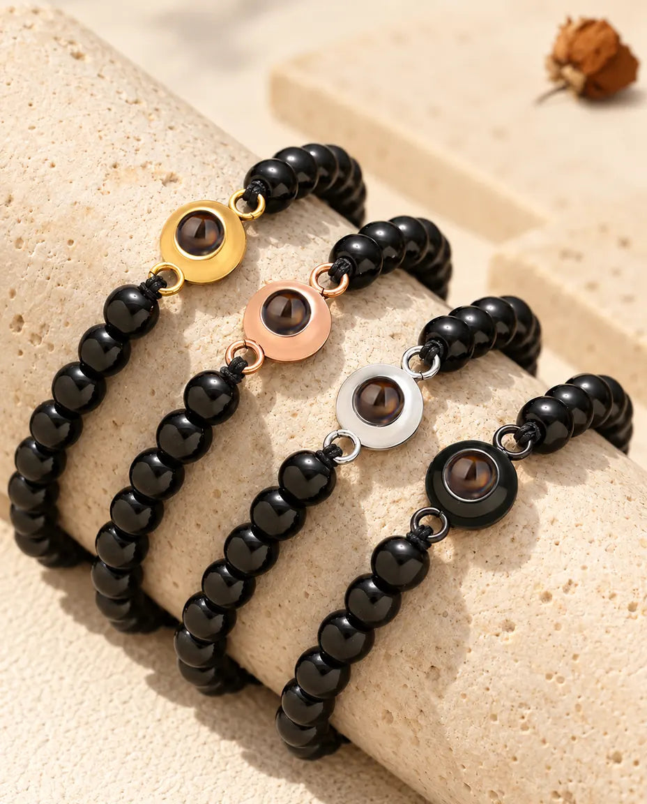 Schwarz glänzende Perlenarmbänder in allen vier Charm-Farben auf einem Travertinblock