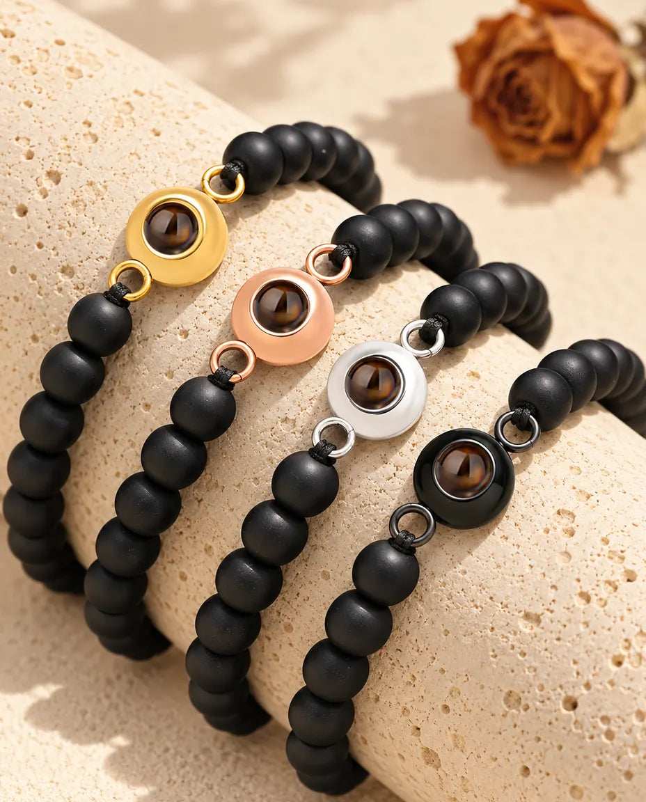 Schwarz matte Perlenarmbänder in jeder Charm-Farbe über einem Travertinblock