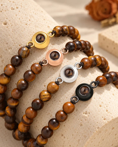Armbänder aus Tigerauge-Perlen in allen vier Charm-Farben auf einem Travertinblock