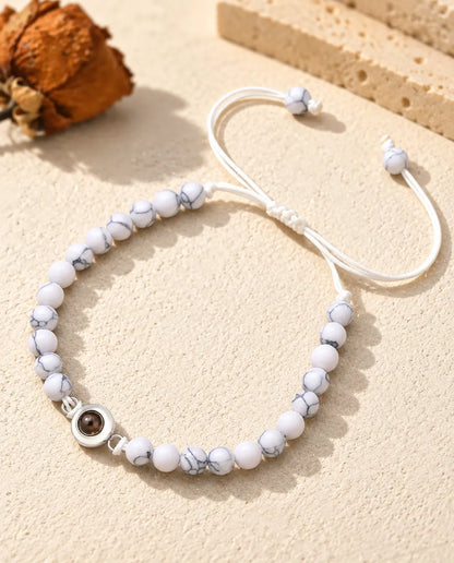 Weiß marmoriertes Perlenarmband mit silberfarbenem Charm und Schiebeknoten