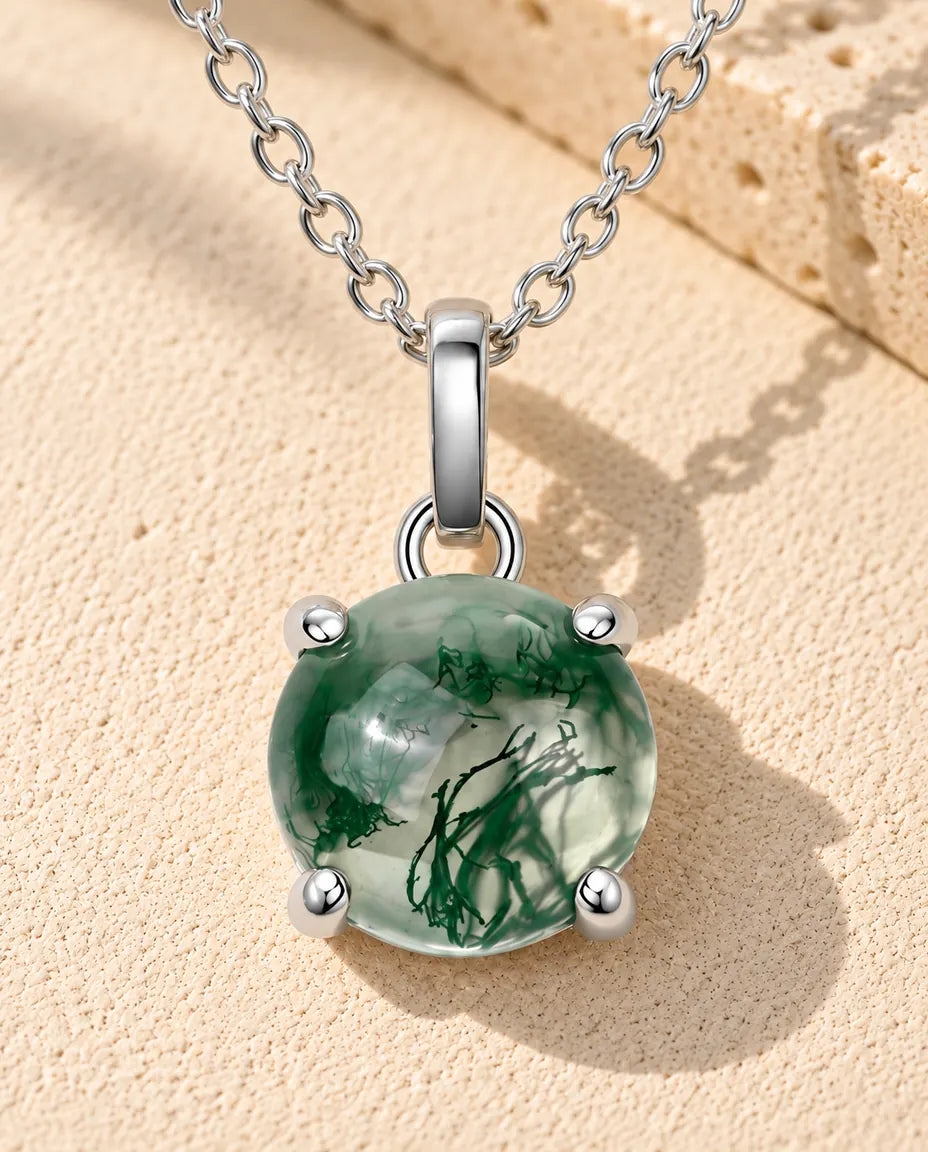 Runde Moosachat Kette aus 925 Sterlingsilber - auf heller Strukturfläche neben einem Travertinblock liegend