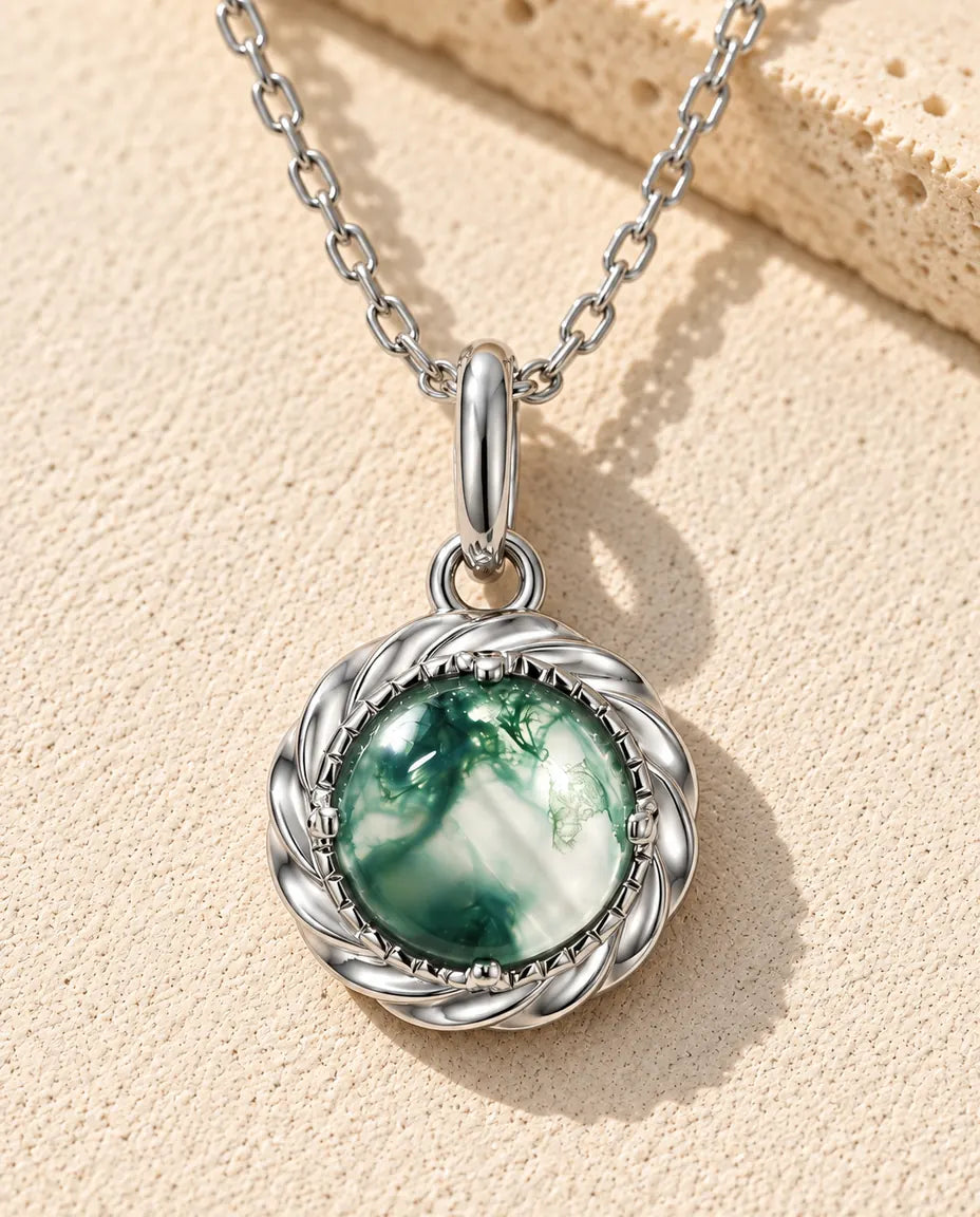 Runder Moosachat Anhänger Kette aus 925 Sterlingsilber - auf heller Strukturfläche neben einem Travertinblock liegend