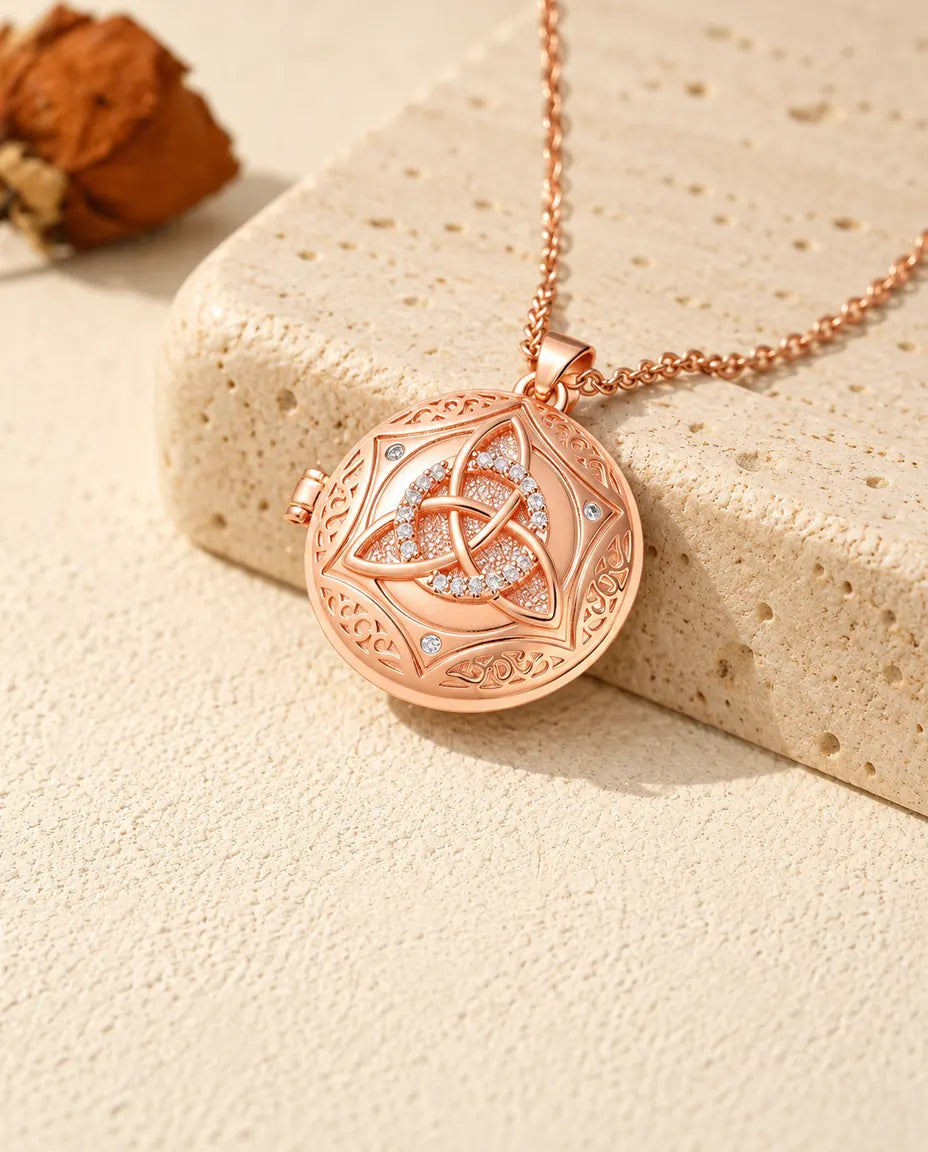 Roségoldfarbenes Foto-Medaillon mit keltischem Knoten und Zirkonia-Ring auf Travertin