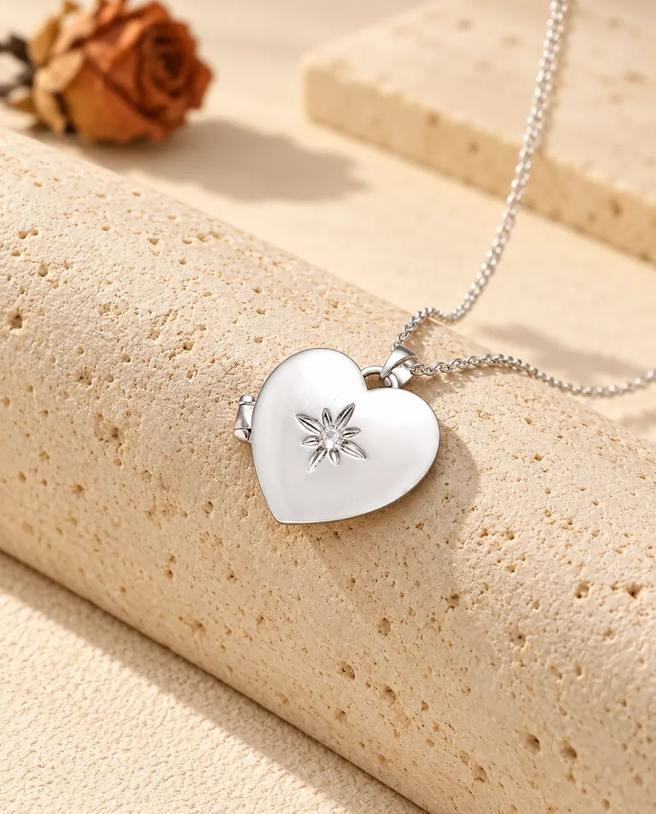 Personalisiertes satiniertes Herz-Foto-Medaillon silberfarben mit kleiner Sternblume, auf einem Travertinblock