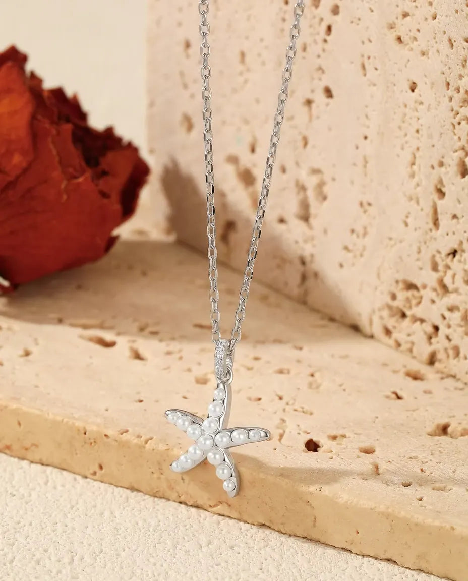Seestern Kette aus 925 Sterlingsilber - Anhänger über der Kante einer Travertinplatte hängend