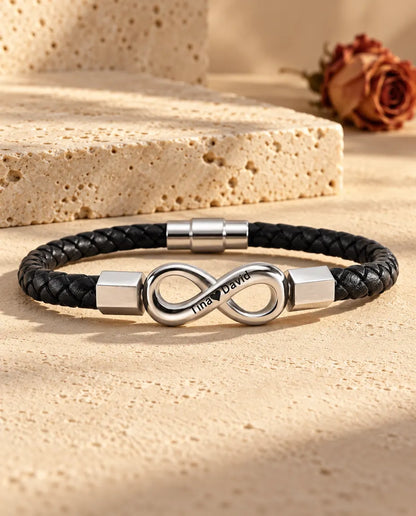 Silberfarbenes Unendlichkeitszeichen aus Edelstahl mit sechskantigen Endkappen an einem schwarzen Kunstlederarmband