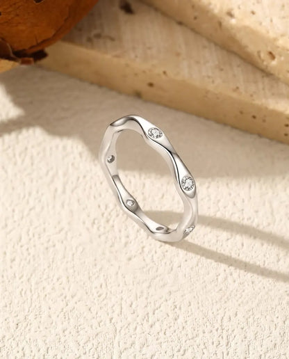 Welliger Moissanit Ring aus 925 Sterlingsilber - aufrecht stehend auf heller Strukturfläche
