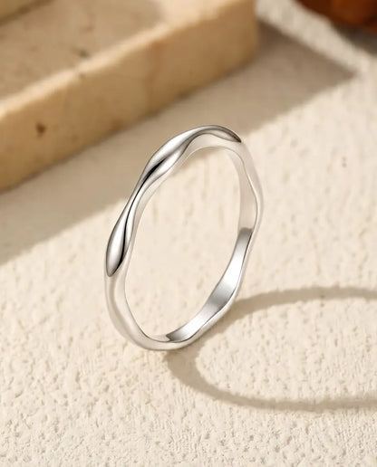 Welliger Ring aus 925 Sterlingsilber - aufrecht stehend auf heller Strukturfläche