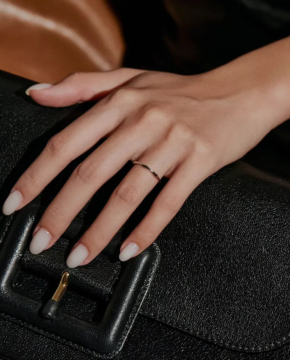 Welliger Ring aus 925 Sterlingsilber - an einer Hand auf einer schwarzen Tasche getragen
