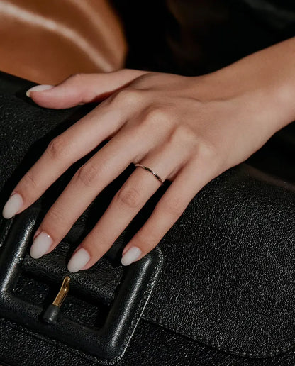 Welliger Ring aus 925 Sterlingsilber - an einer Hand auf einer schwarzen Tasche getragen
