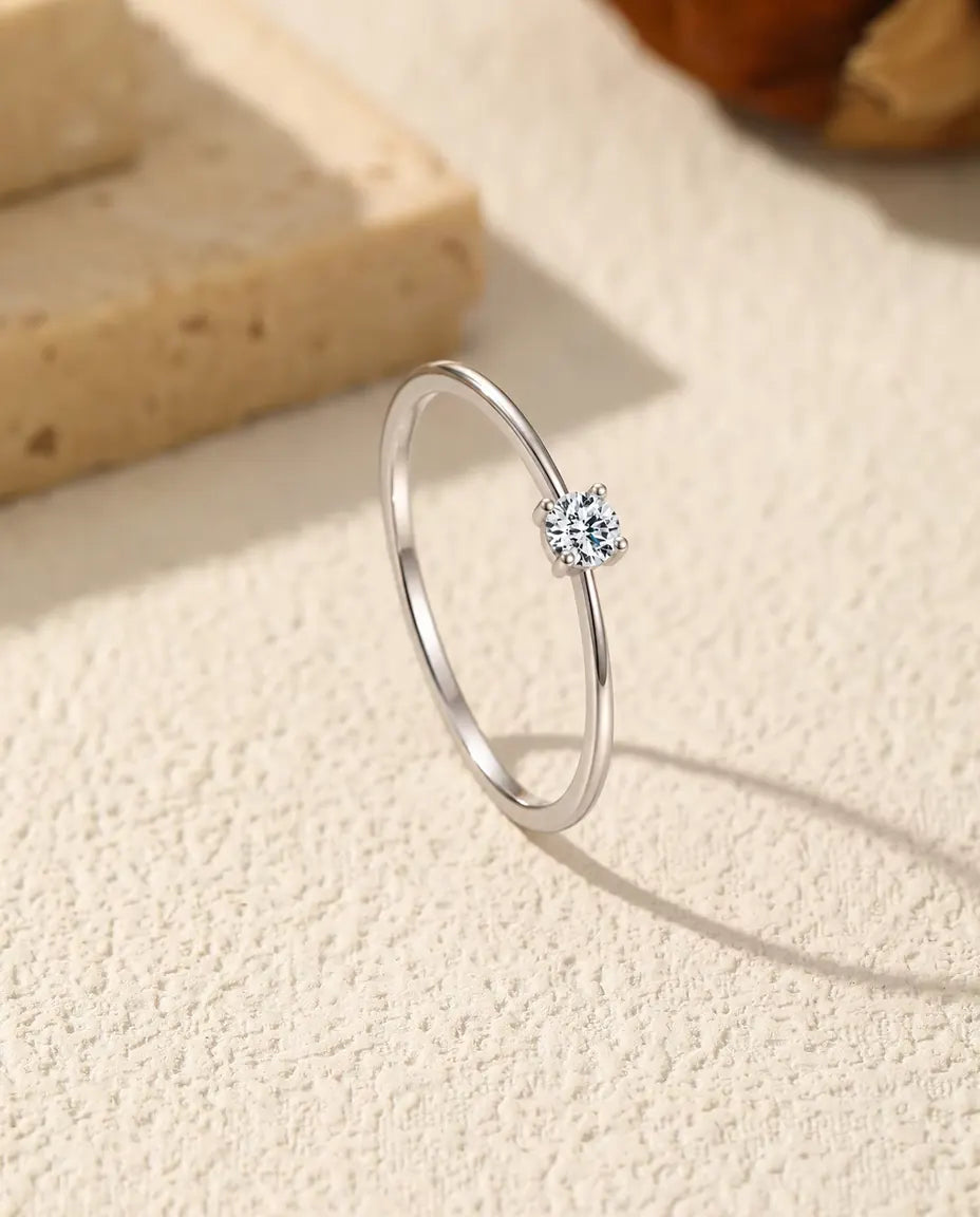 Zarter Moissanit Solitär Ring aus 925 Sterlingsilber - aufrecht stehend auf heller Strukturfläche