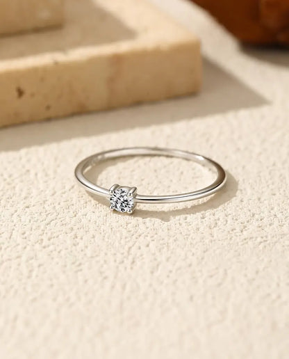 Zarter Moissanit Solitär Ring aus 925 Sterlingsilber - flach liegend auf heller Strukturfläche