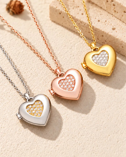 Zweifarbiges Herz-Foto-Medaillon in Silber-, Roségold- und Goldfarbe schräg auf cremefarbenem Putz